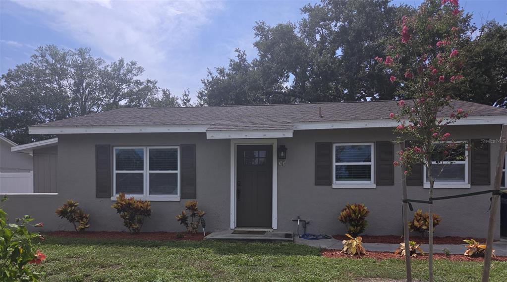 A single-story gray house with dark shutters, a front door, and landscaping under a blue sky — 20 S SATURN AVENUE, CLEARWATER, FL