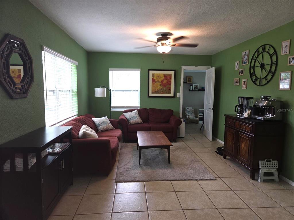 A living room features green walls, a red sofa, a coffee table, and tile flooring — 20 S SATURN AVENUE, CLEARWATER, FL