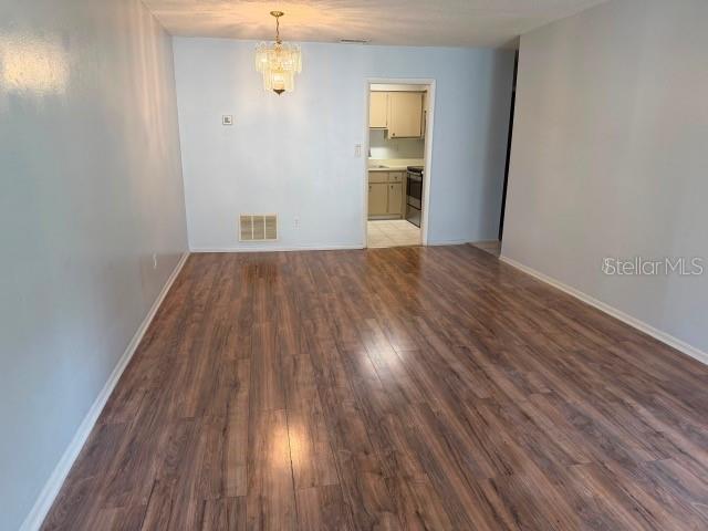 A living room with light gray walls, wood-look laminate flooring, and a doorway to the kitchen — 7523 DOLONITA DRIVE UNIT 7523, TAMPA, FL