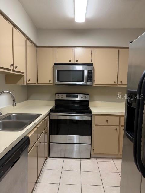 A kitchen features beige cabinets, stainless steel appliances, and a double sink with a faucet — 7523 DOLONITA DRIVE UNIT 7523, TAMPA, FL