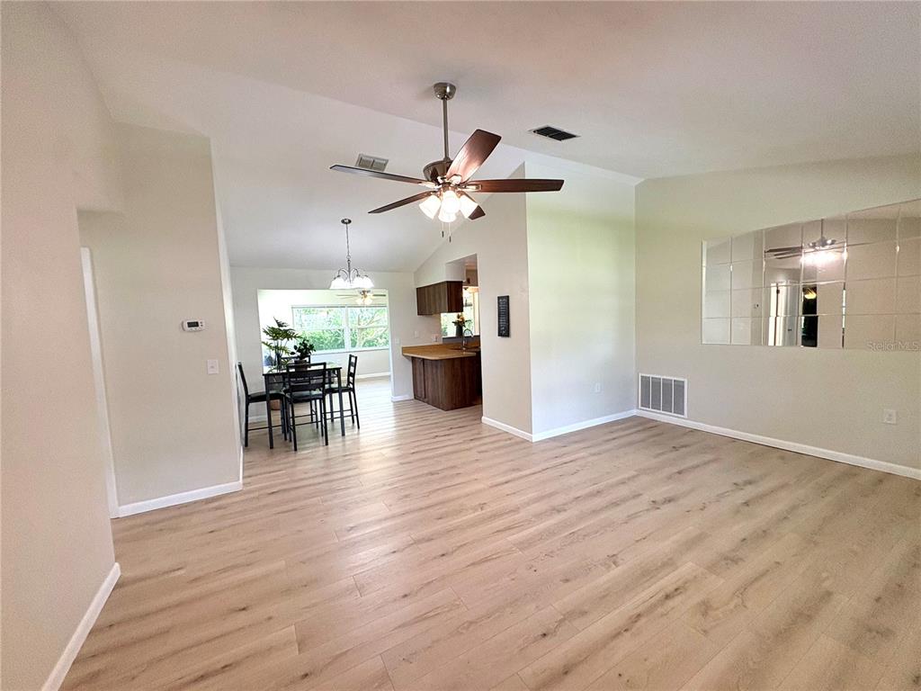 An open-concept living and dining area features light wood-look flooring and a vaulted ceiling — 3123 N MAIDENCANE DRIVE, BEVERLY HILLS, FL