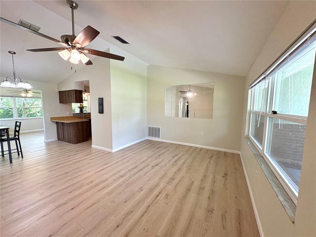 An open living area with light wood-look flooring, a ceiling fan, and a mirrored wall — 3123 N MAIDENCANE DRIVE, BEVERLY HILLS, FL