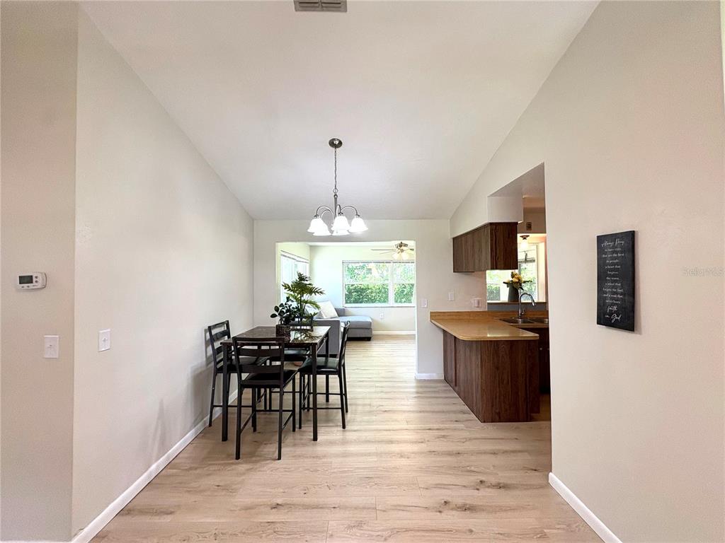 A dining area with wood-look flooring connects to a kitchen with a breakfast bar — 3123 N MAIDENCANE DRIVE, BEVERLY HILLS, FL