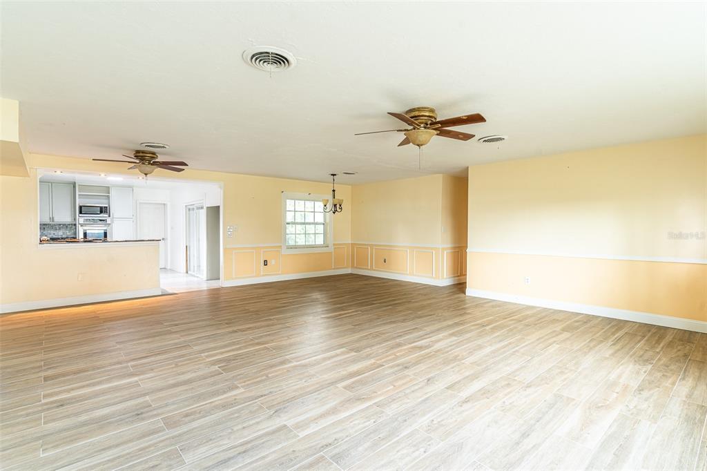 An open-concept living and dining area features light-colored wood-look tile flooring and yellow walls — 3510 LAKEVIEW DRIVE, SEBRING, FL