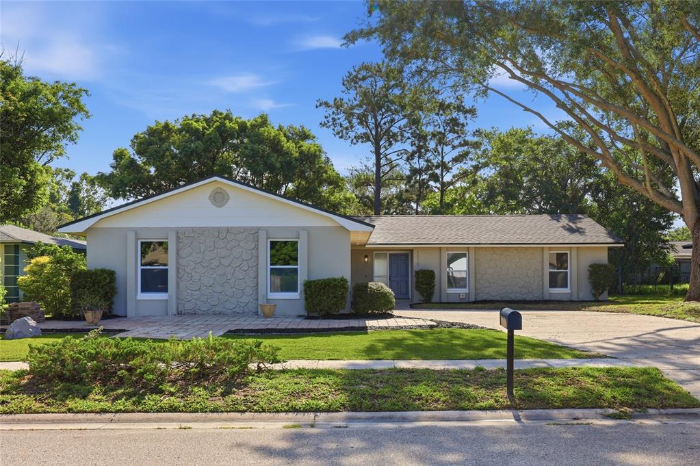 A single-story house with a stone facade, a blue front door, and a paved driveway — 1011 MANCHESTER CIRCLE, WINTER PARK, FL