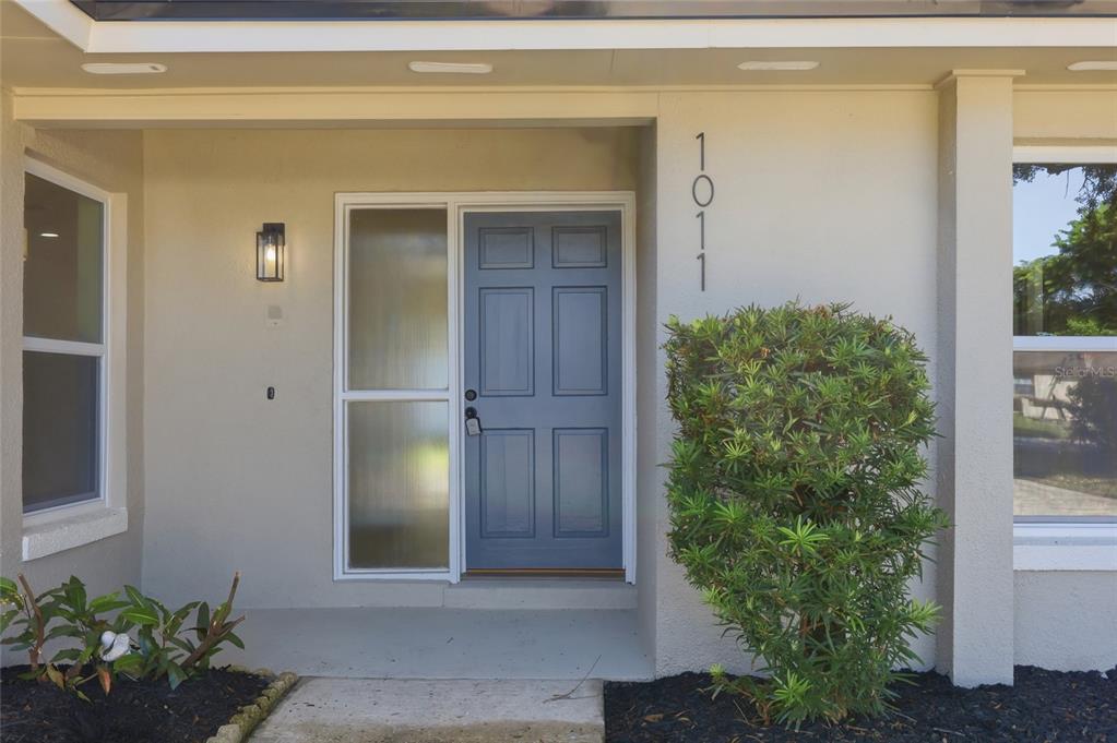The front entrance of a house features a blue door, a sidelight, and house number 1011 — 1011 MANCHESTER CIRCLE, WINTER PARK, FL