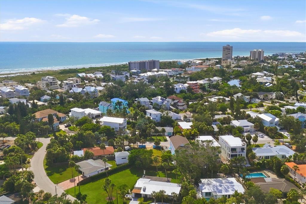 An aerial view of a coastal neighborhood with houses, lush trees, and the ocean beyond — 5375 CALLE FLORIDA, SARASOTA, FL