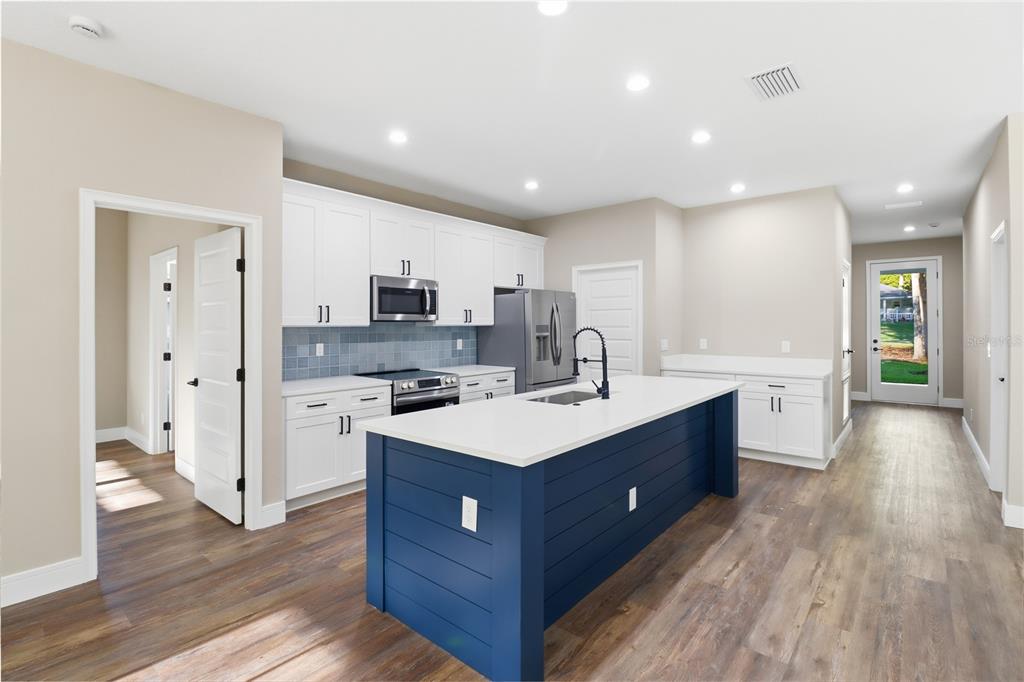 A kitchen features white cabinets, a blue island with a sink, and wood-look flooring — 19126 SW 101ST STREET, DUNNELLON, FL