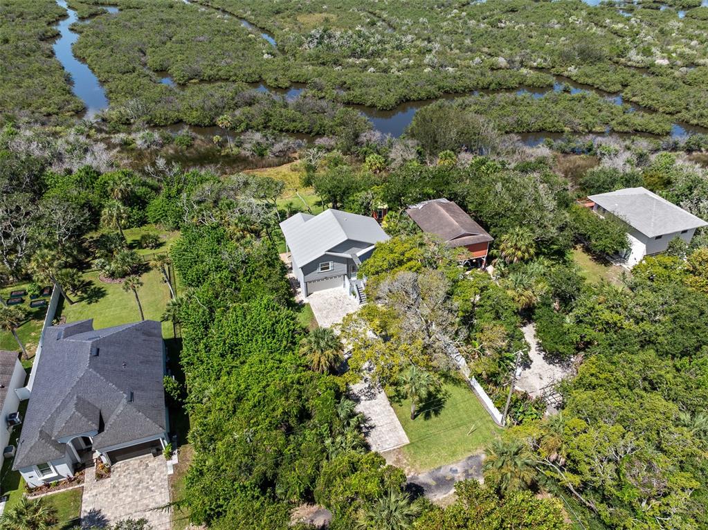 An aerial view shows several houses surrounded by dense trees and a winding waterway — 1843 OAK PLACE, FLAGLER BEACH, FL