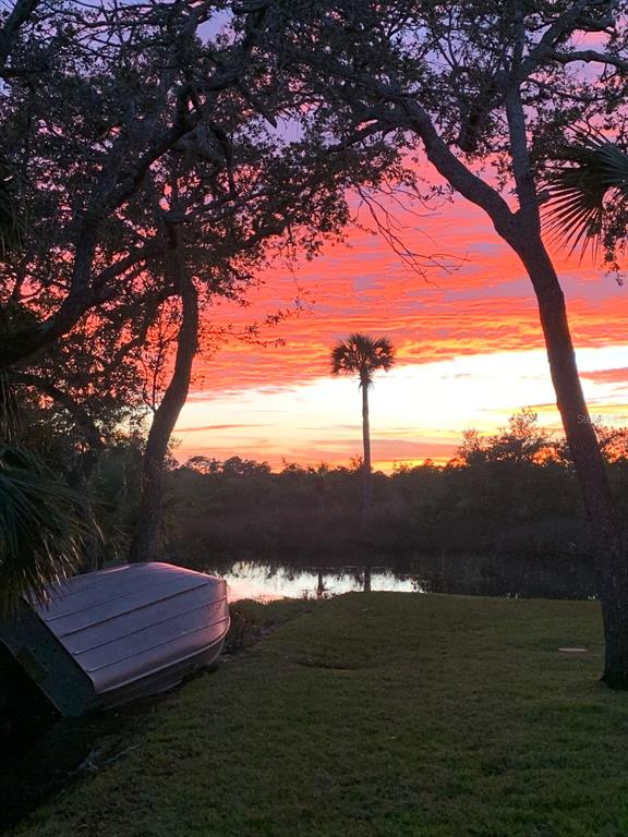 A small boat rests on the grass near a pond under a vibrant sunset sky — 1843 OAK PLACE, FLAGLER BEACH, FL