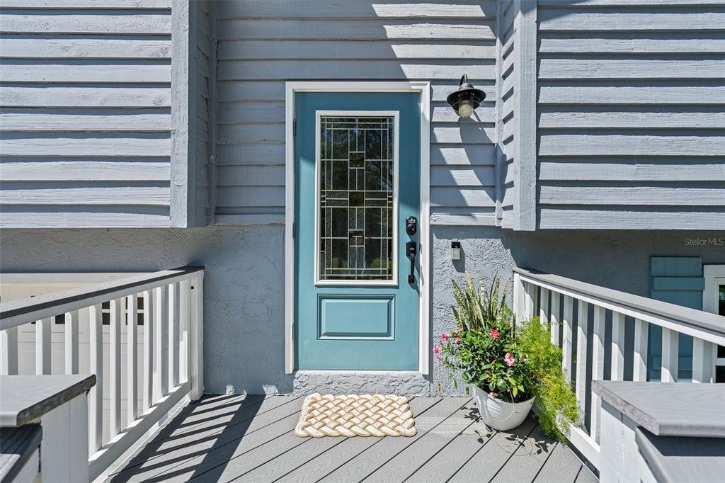 A teal front door with a glass insert sits on a gray wooden deck — 1843 OAK PLACE, FLAGLER BEACH, FL
