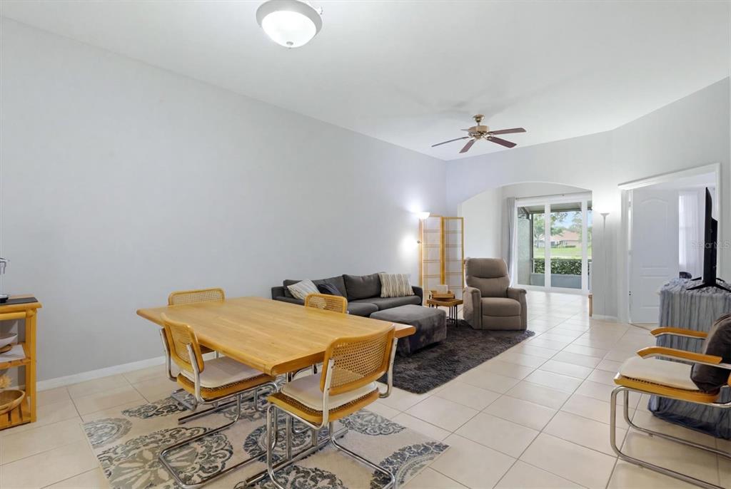 A living and dining area with tile floors, a wooden table, and a gray sofa — 2175 LYNX RUN, NORTH PORT, FL