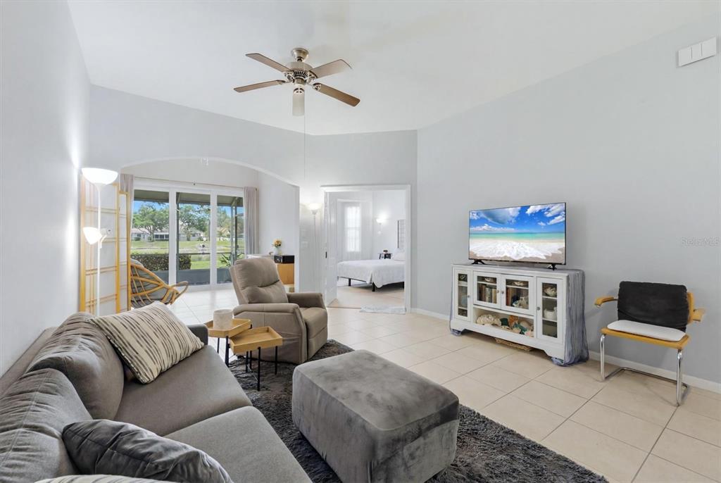 A living room features a grey sofa, a recliner, a television console, and tile flooring — 2175 LYNX RUN, NORTH PORT, FL