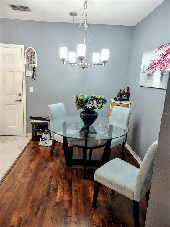 A dining area features a glass-topped table, four light blue chairs, and a modern chandelier — 5550 E MICHIGAN STREET UNIT 2328, ORLANDO, FL