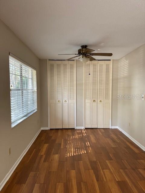 A bedroom with wood-look flooring, a ceiling fan, and two sets of white louvered closet doors — 225 3RD, MOUNT DORA, FL
