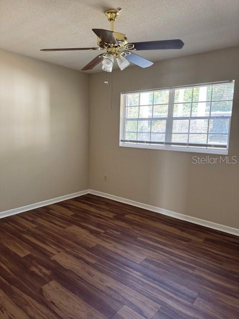 An empty room features wood-look flooring, beige walls, a ceiling fan, and a large window — 225 3RD, MOUNT DORA, FL