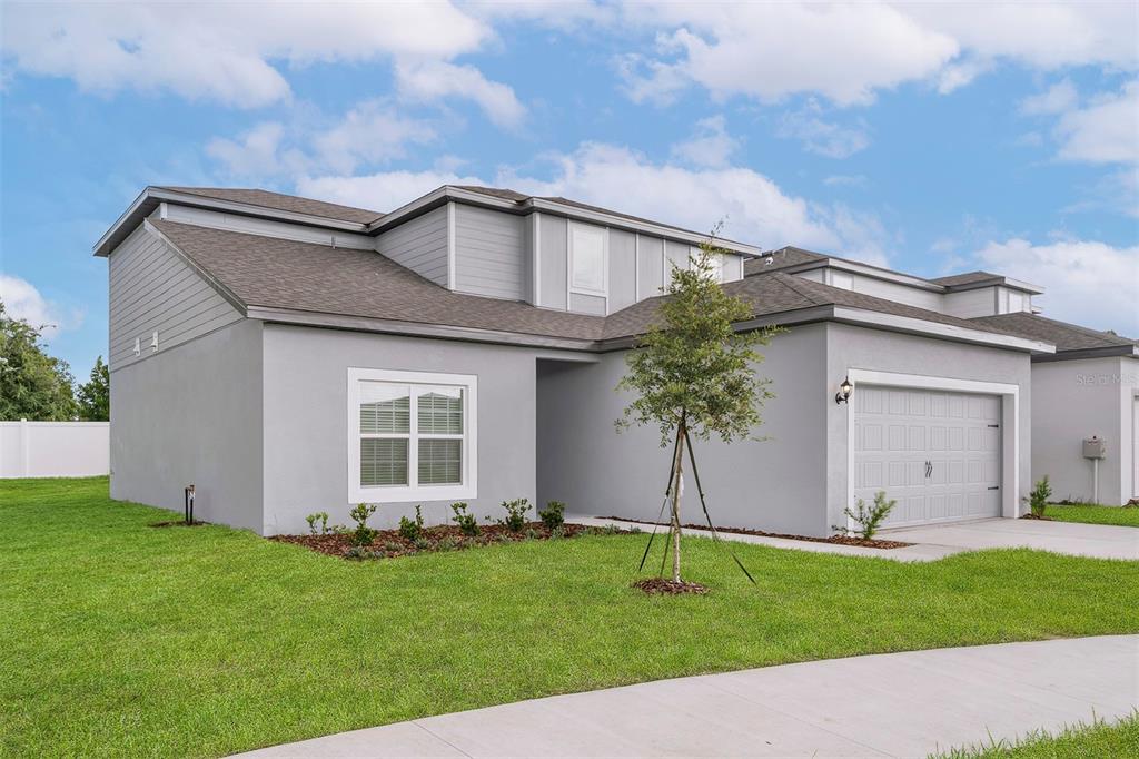 A two-story gray house with a single-car garage and a small front yard — 13348 TULA LOOP, ASTATULA, FL