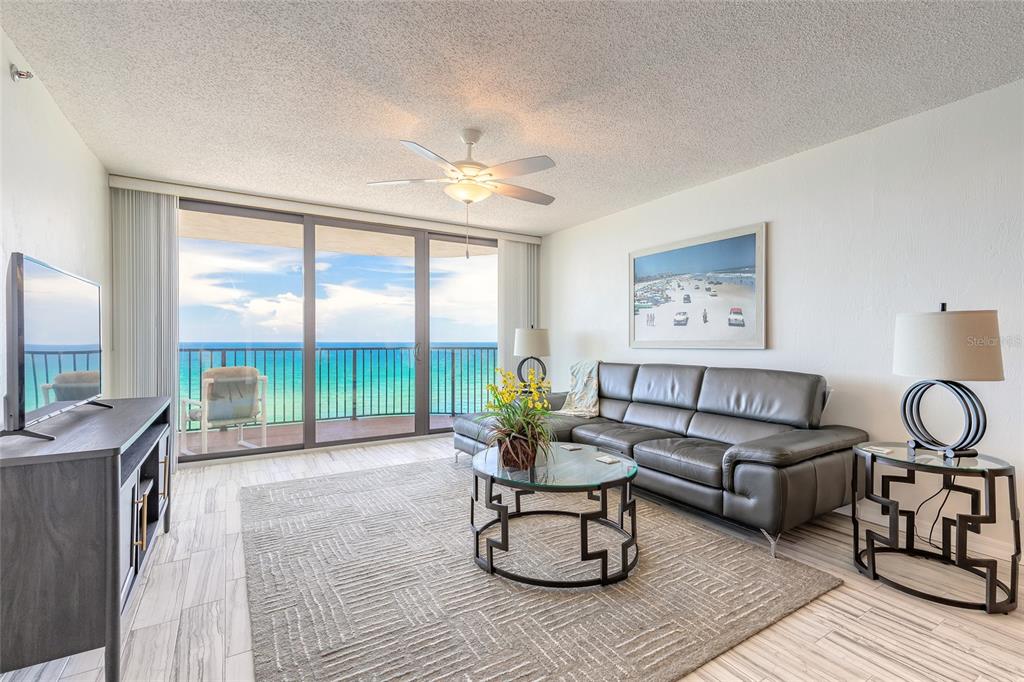 A living room features a gray leather sectional, glass coffee table, and sliding doors to a balcony — 3757 S ATLANTIC AVENUE UNIT 1104, DAYTONA BEACH SHORES, FL