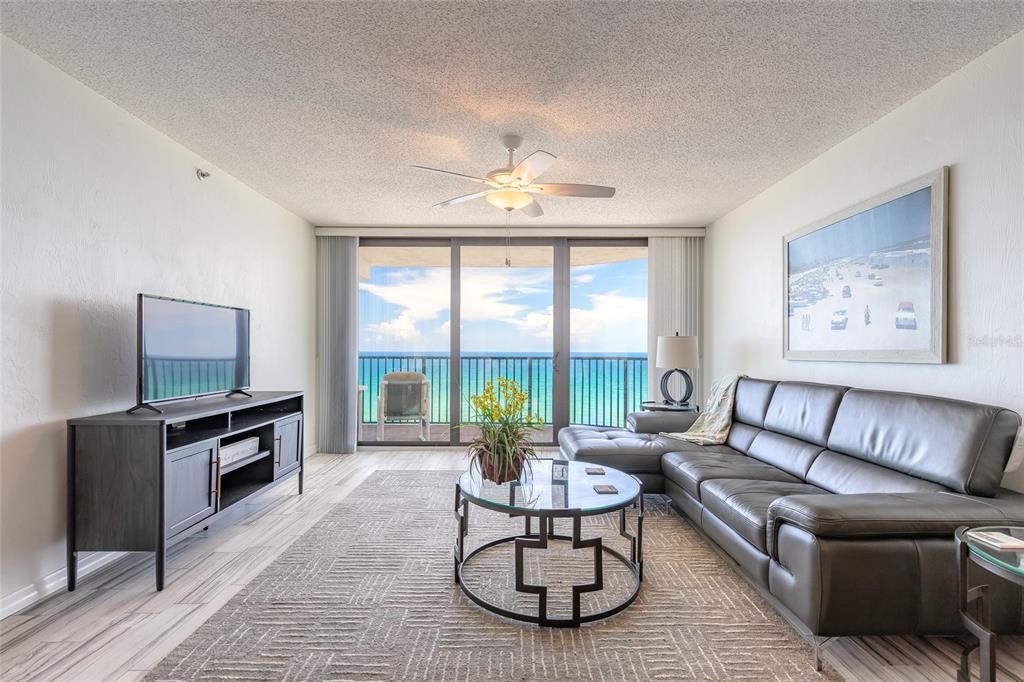 A living room features a gray leather sectional, a glass coffee table, and ocean views — 3757 S ATLANTIC AVENUE UNIT 1104, DAYTONA BEACH SHORES, FL