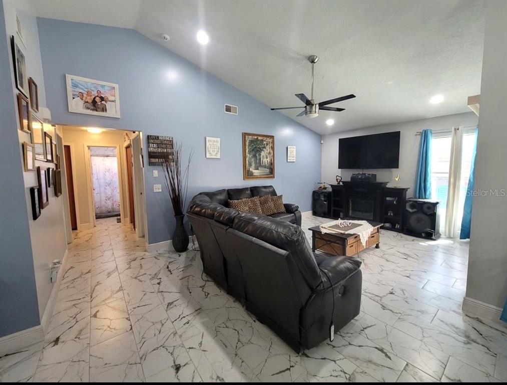 A living room features light blue walls, a vaulted ceiling, and white marble-patterned tile flooring — 2609 MILL RUN BOULEVARD, KISSIMMEE, FL