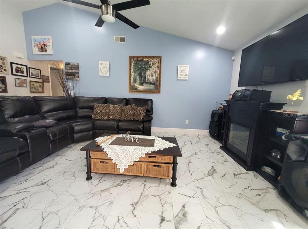 A living room features a black leather sectional, a coffee table, and a wall-mounted television — 2609 MILL RUN BOULEVARD, KISSIMMEE, FL