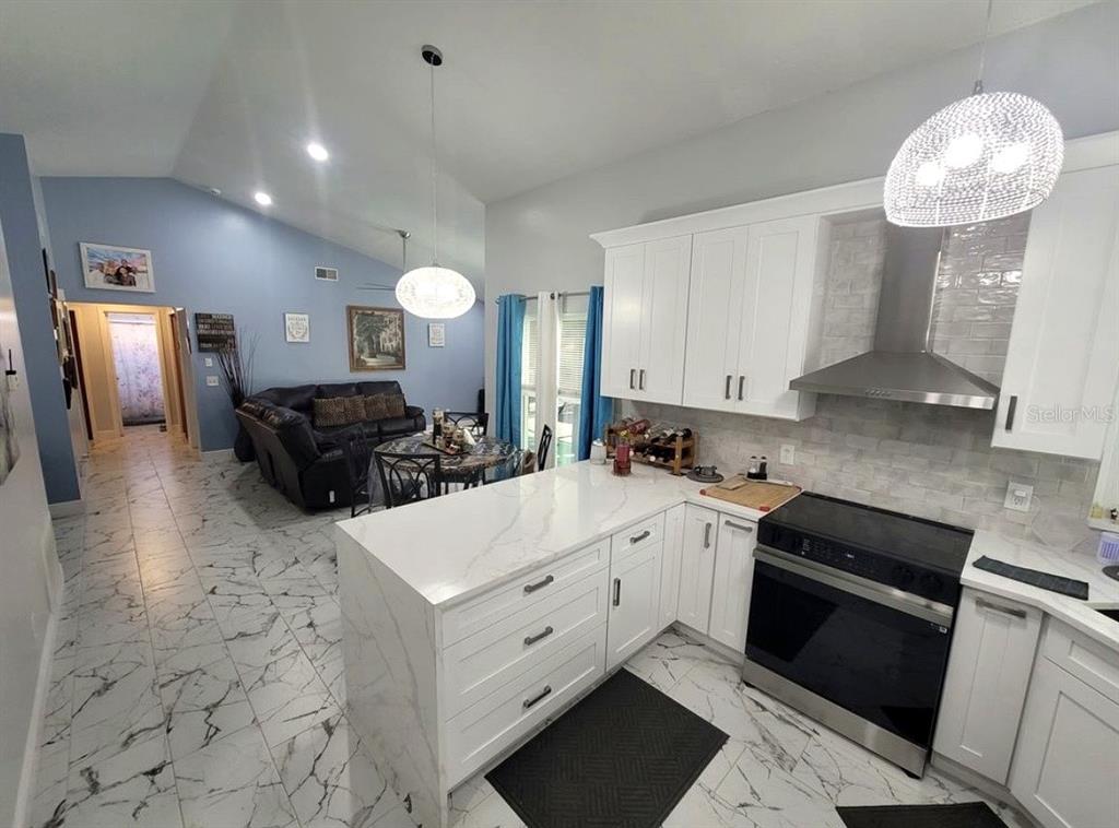 A kitchen with white cabinets and marble-look countertops overlooks a living area with tiled floors — 2609 MILL RUN BOULEVARD, KISSIMMEE, FL