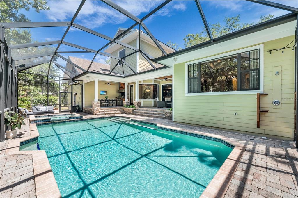 A two-story house with light green siding, stone accents, a paved driveway, and a basketball hoop — 5911 RIVER FOREST CIRCLE, BRADENTON, FL