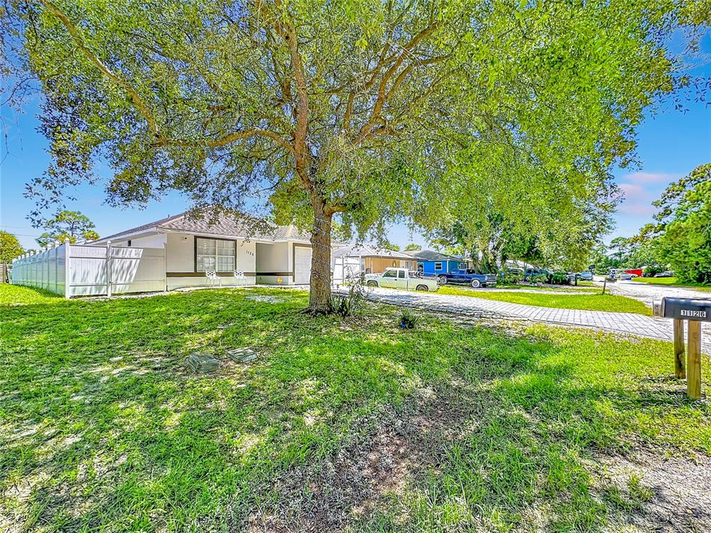 A single-story house with a large tree in the front yard and a paved driveway — 1126 15TH AVENUE SW, VERO BEACH, FL