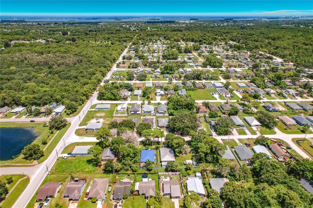 An aerial view shows a suburban neighborhood with houses, trees, and a small pond — 1126 15TH AVENUE SW, VERO BEACH, FL