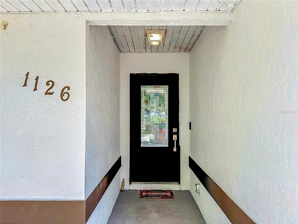 A covered entryway features a black front door, white stucco walls, and house number 1126 — 1126 15TH AVENUE SW, VERO BEACH, FL
