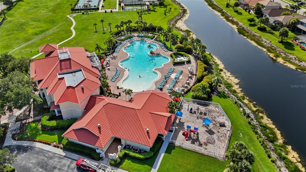 An aerial view shows a clubhouse with a red roof, swimming pool, and playground — 3390 WESTON MANOR DRIVE, ALVA, FL