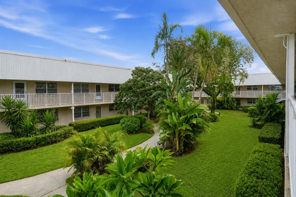 An exterior view of a two-story apartment complex with a landscaped courtyard and walking path — 10033 64TH AVENUE N UNIT 16, ST PETERSBURG, FL