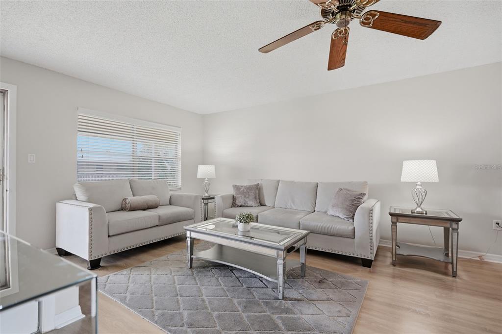 A living room features light gray sofas, a mirrored coffee table, and a ceiling fan — 10033 64TH AVENUE N UNIT 16, ST PETERSBURG, FL