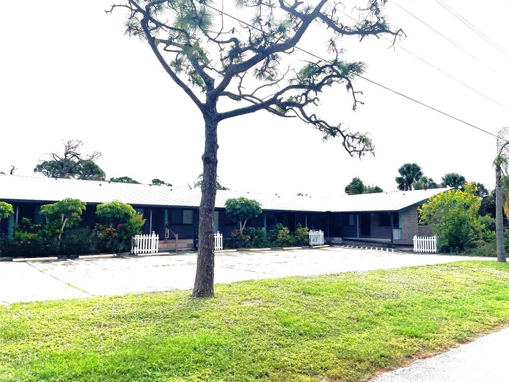 A single-story building with a metal roof and a large tree in the front parking — 9000 GRIGGS ROAD UNIT C, ENGLEWOOD, FL