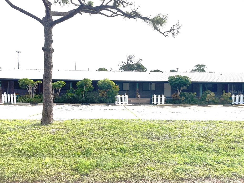 A single-story building with a flat roof and a parking lot in the foreground — 9000 GRIGGS ROAD UNIT C, ENGLEWOOD, FL