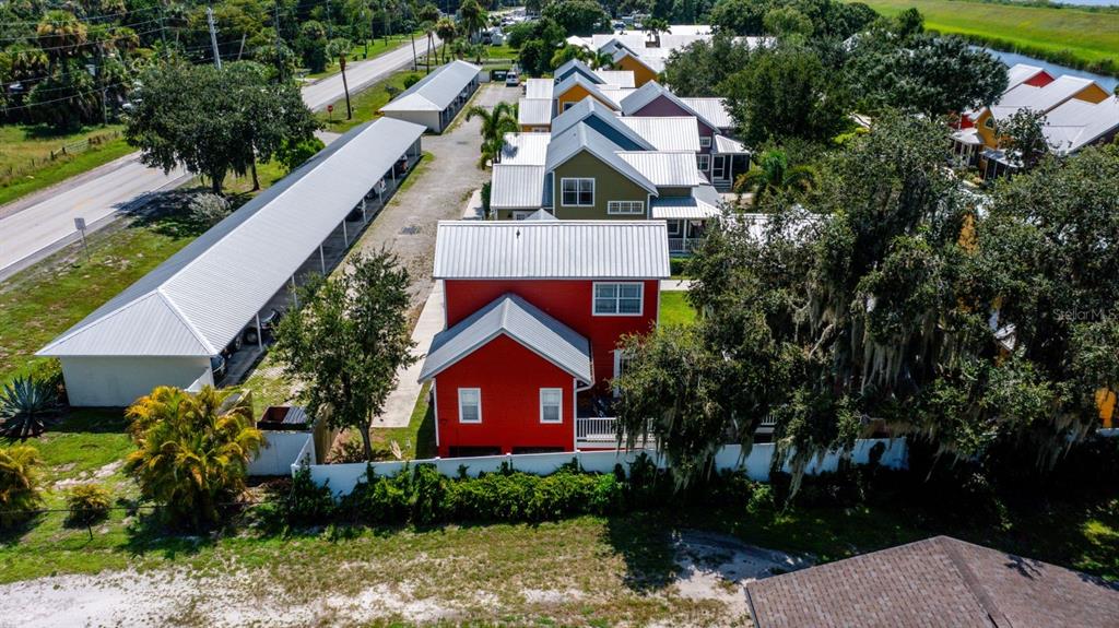 An aerial view shows a red house with a metal roof next to covered parking — 4334 US HIGHWAY 441 SE UNIT 24, OKEECHOBEE, FL