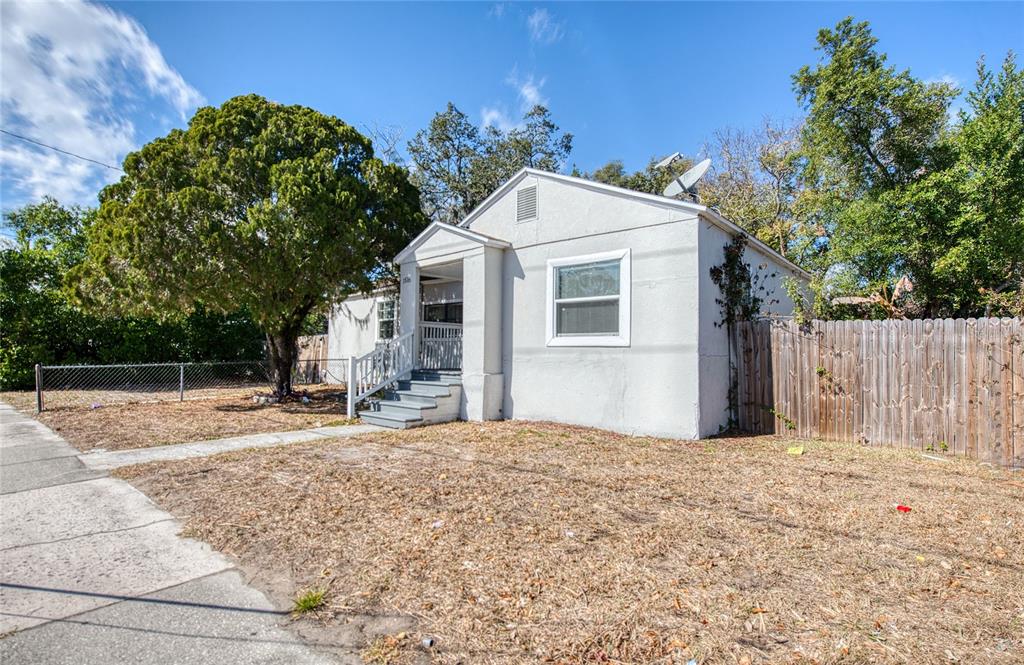 A single-story white house with a front porch and a wooden fence sits outdoors — 1516 E WATERS AVENUE, TAMPA, FL