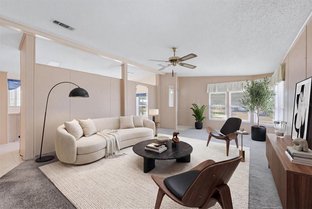 A living room features a curved sofa, two wooden chairs, and a round coffee table — 8420 IMPERIAL CIRCLE, PALMETTO, FL