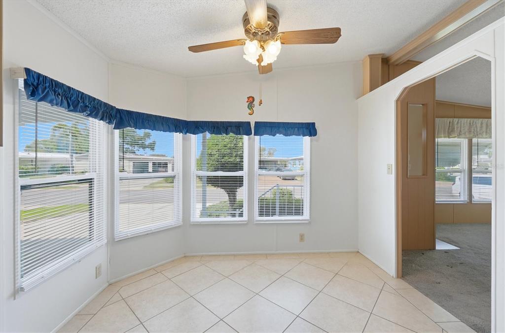 A bright dining area features tiled floors, a bay window, and a ceiling fan — 8420 IMPERIAL CIRCLE, PALMETTO, FL