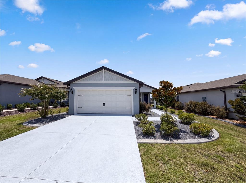 A single-story house with a white garage door, gray siding, and a concrete driveway — 8332 SW 54TH LOOP, OCALA, FL