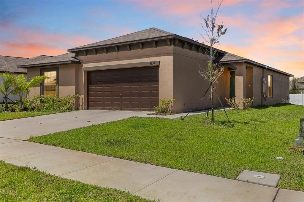 A single-story house with a brown garage, tan stucco exterior, and a green lawn — 4357 FABULOUS FINCH LANE, BARTOW, FL