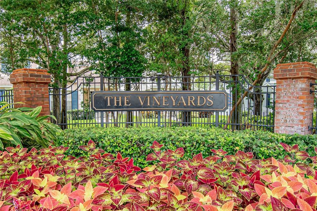 A sign reading The Vineyards stands behind a bed of colorful coleus plants and trees — 10807 SIERRA VISTA PLACE, TAMPA, FL