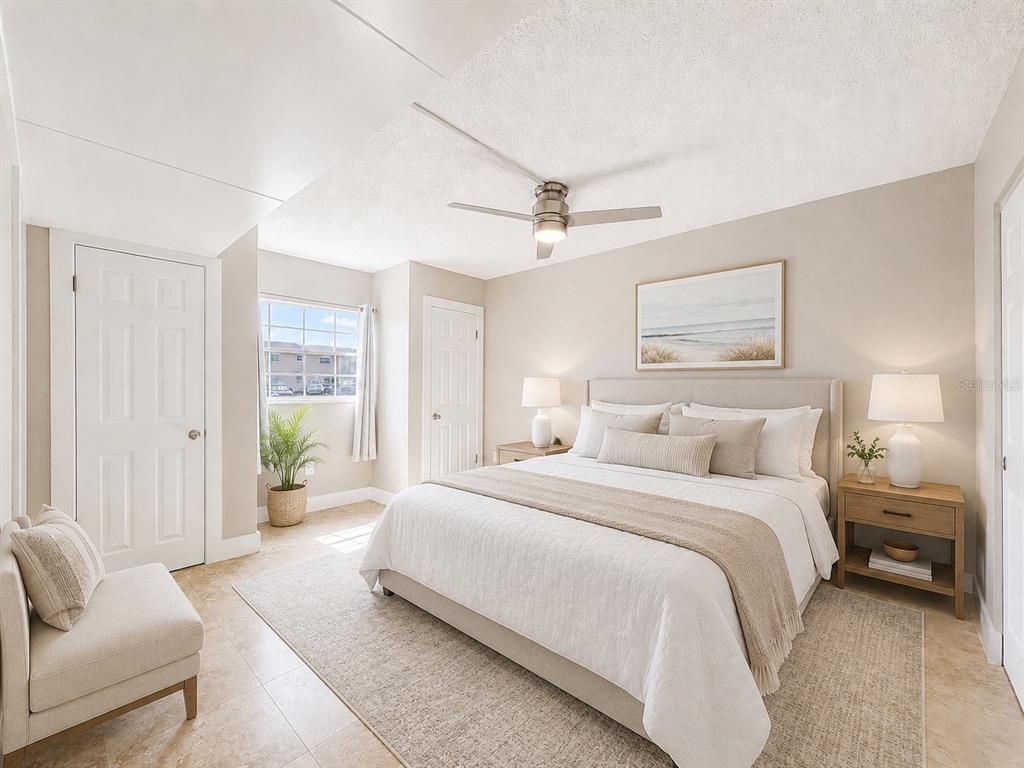A neutral-toned bedroom features a queen bed, two nightstands, a ceiling fan, and tile flooring — 8818 BAY POINTE DRIVE UNIT 108, TAMPA, FL