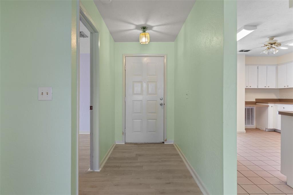 A light green entryway features a white front door, wood-look flooring, and a ceiling light — 909 W BEAKRUSH LANE, BEVERLY HILLS, FL