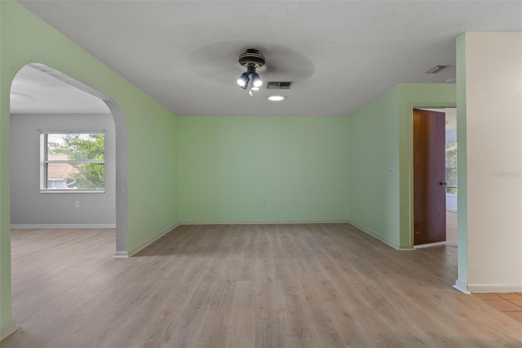 A room with light green walls, wood-look flooring, and an arched entryway — 909 W BEAKRUSH LANE, BEVERLY HILLS, FL