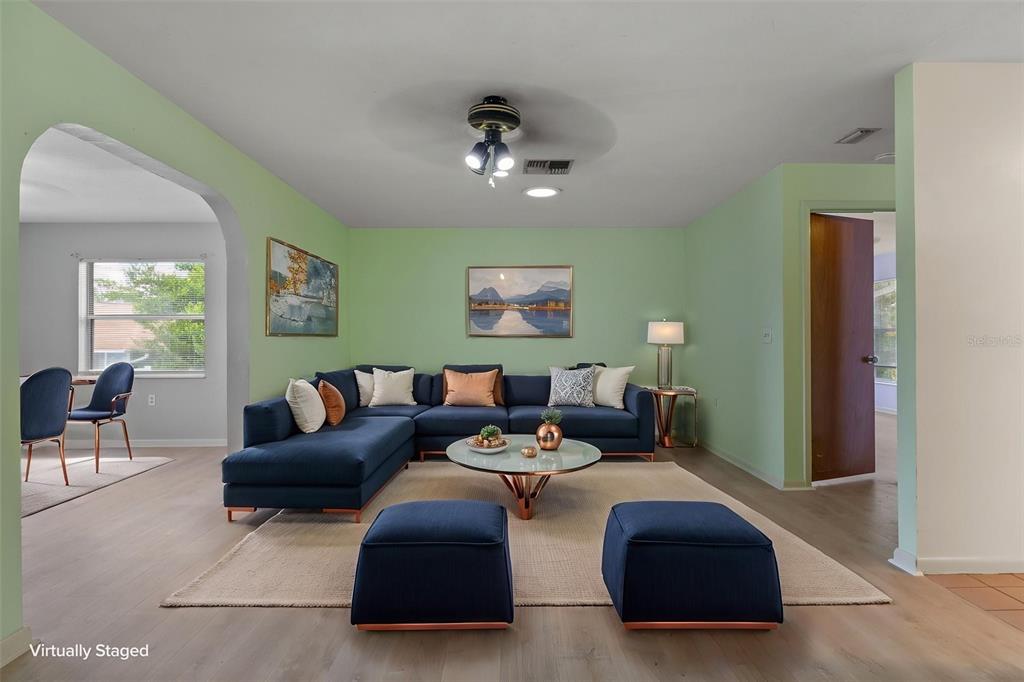 A living room features a blue sectional sofa, two ottomans, and light green walls — 909 W BEAKRUSH LANE, BEVERLY HILLS, FL