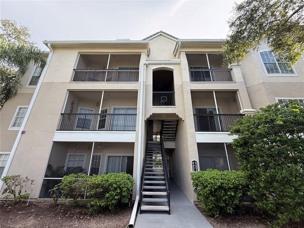 The exterior of a three-story apartment building features screened balconies and an outdoor staircase — 5152 NORTHRIDGE ROAD UNIT 202, SARASOTA, FL