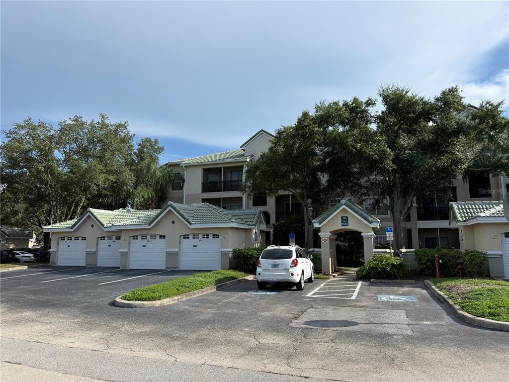 A multi-story apartment building features a row of garages and a covered entryway — 5152 NORTHRIDGE ROAD UNIT 202, SARASOTA, FL