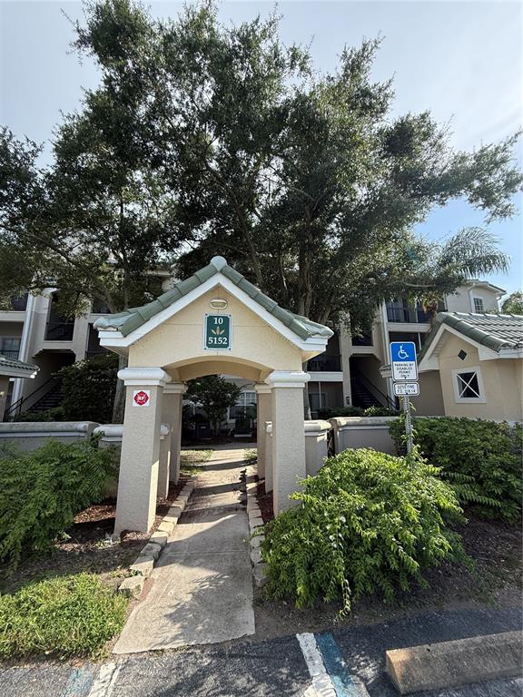 A concrete walkway leads to the entrance of a multi-story apartment building under large trees — 5152 NORTHRIDGE ROAD UNIT 202, SARASOTA, FL