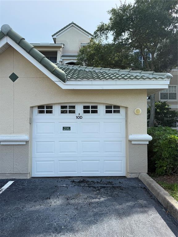 A white garage door labeled 10D is attached to a tan stucco building with a tiled roof — 5152 NORTHRIDGE ROAD UNIT 202, SARASOTA, FL